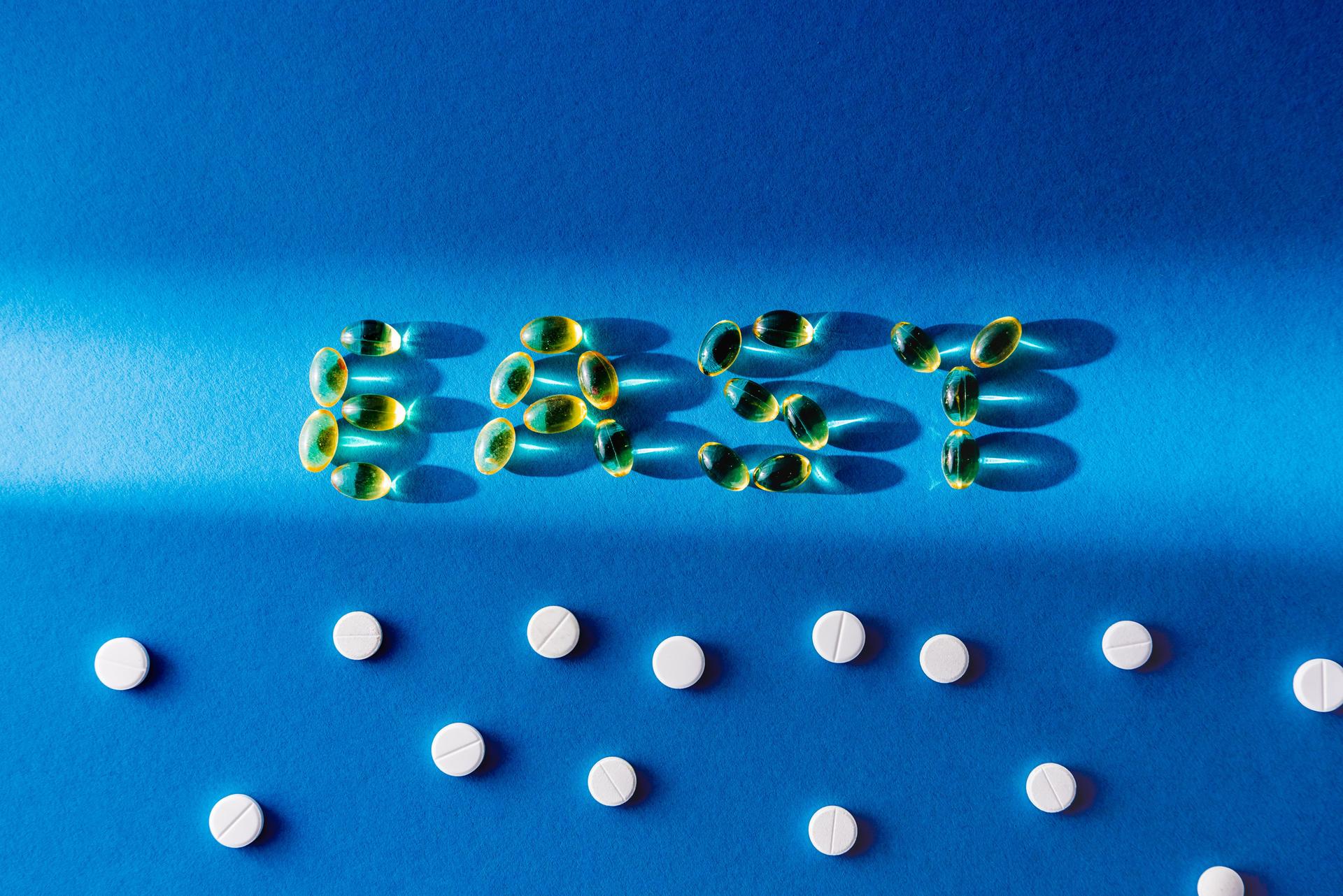top view of lettering easy by pills near white tablets on blue background with sunlight